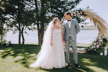 Wedding portrait of smiling newlyweds. Stylish groom in a gray checkered suit and a cute blonde...