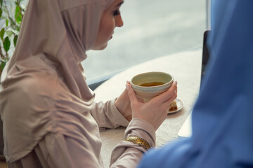 Close up hands. Beautiful arab women meeting at cafe or restaurant, friends or business meeting. Spending time together, talking, laughting. Muslim lifestyle. Stylish and happy models with make up.