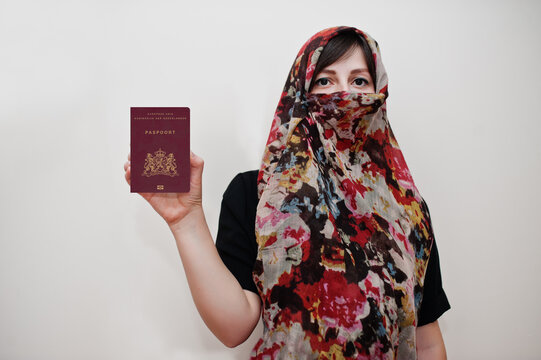 Young arabian muslim woman in hijab clothes hold Netherlands passport on white wall background, studio portrait.