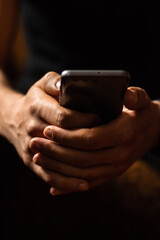 Person using smartphone. Close-up of a smartphone in male hands in a cozy warm home environment