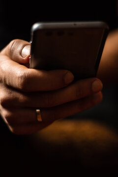 Mobile Phone In Male Hand With Wedding Ring On Finger With Blurred Background Close Up