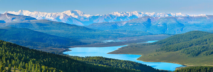 Mountain valley with a lake. Snow-capped peaks and blue sky.