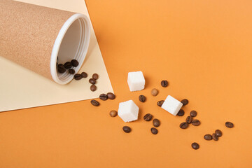 Thermo mug, scattered coffee grains and white sugar cubes on brown and beige geometric background
