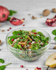 Spinach, pomegranate, pear and cottage cheese salad in a glass bowl.