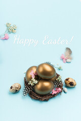 Easter Decoration with golden eggs, quail feathers, dried flowers on blue background. Happy Easter card concept.