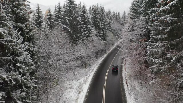 4K Aerial view of a black SUV driving in the winter scenery landscape from the Romanian Mountains