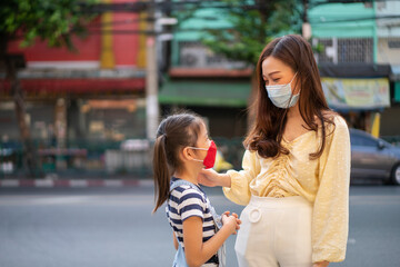 Asian beautiful woman and her daughter wear protection mask for corona virus or covid-19 virus outbreak and pm 2.5 in a city. Corona virus, Covid-19, virus outbreak or social distancing concept
