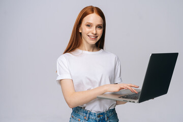 Cute charming young business woman or student holding laptop computer and looking at camera on...