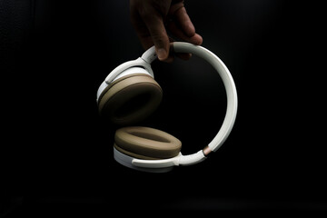 man hand holding headphones on black background. music concept
