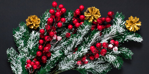 Christmas tree decorations on a dark background. Green fir branches with snow, golden pine cones...