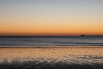 Last rays of sun at sunset and its reflection in the sky and in the sea