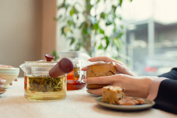 Close up female hands pouring tea in cup at restaurant or cafe, daily lifestyle. Comfortable atmosphere, warm, leisure, drinks and food. Friends, family or business meeting.