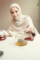 Laughting, looks happy. Beautiful arab woman meeting at cafe or restaurant with friend, spending time with cup of tea. Muslim lifestyle. Stylish and happy model with make up in comfortable interior.