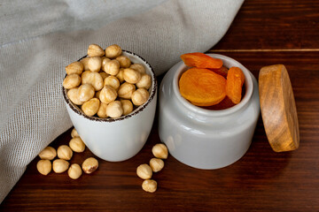 Bowls with hazelnut and dried apricots on wooden table
