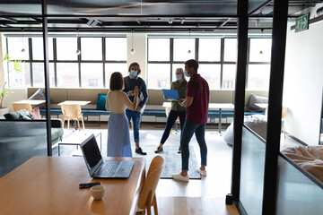 Diverse group of business colleagues wearing face masks standing in casual meeting