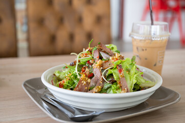 Spicy vegetables with pork and ice coffee on the table