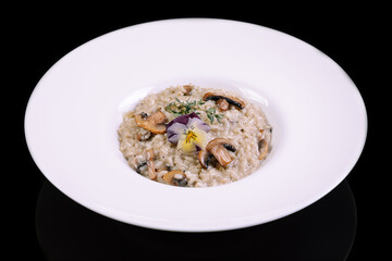 Risotto with champignon,spinach and parmesan  on white plate isolatet on black background