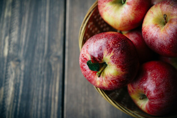 Red apples in a wicker basket and wooden background