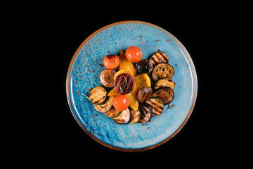 Grilled vegetables (colorful bell peppers, zucchini,  onion, piper, mushrooms, tomatos) with basil and dried herbs on a plate over a dark slate, stone, concrete or wooden plate.Top view.