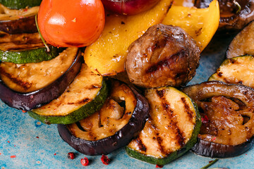 Grilled vegetables (colorful bell peppers, zucchini,  onion, piper, mushrooms, tomatos) with basil and dried herbs on a plate over a dark slate, stone, concrete or wooden plate.Top view.