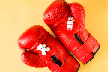 Ampoule and pills on boxing gloves, top view. Foul fight concept. Doping for the athlete.