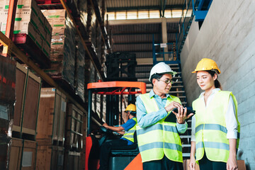 Working at warehouse. asian woman warehouse worker and Manager Shows Digital Tablet Information to further placement in storage department. In Background Stock of Parcels with Products