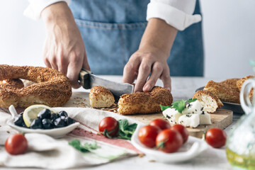 Man prepares Turkish breakfast and bagels, tomato and olive
