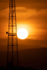 Sunset on telecommunication pole on sihouette sky of golden sunny on hills background, satellite...
