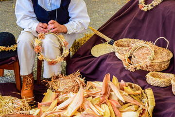 Artisan woman making basketry crowns and headbands from corn husks at a craft fair in Galicia Spain