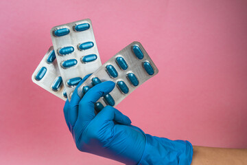 girl with blue latex gloves holding blisters of blue pills in hand