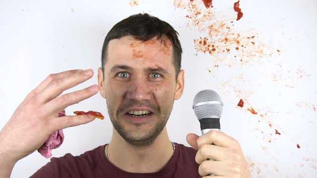 A young attractive stand-up comedian gets shot with tomatoes for poor performance. In slow motion, a tomato smashes against the face of a young stand-up comedian during his speech.