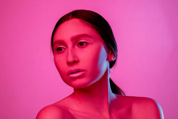 Collarbones. Beautiful east woman's portrait isolated on pink studio background in neon,...