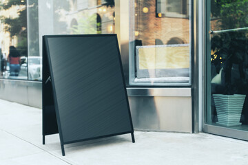 Blank black metal signboard stand near the entrance to the coffee shop, mock up