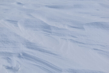 Vom Wind verwehte Schneeoberfläche mit Windstrukturen als winterlicher Hintergrund mit Naturschnee	
