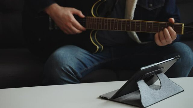 Man learns how to play the guitar. Remote online lesson.
