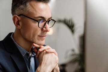 Serious grey man wearing eyeglasses thinking and looking forward