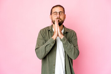 Young man with long hair look holding hands in pray near mouth, feels confident.