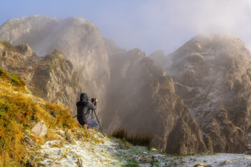 A photographer taking a photo with the tripod in the snowy winter sunset, on the mountain of Pe&ntilde;as de Aya in the town of Oiartzun near San Sebasti&aacute;n, Gipuzkoa. Basque Country