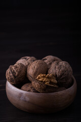 A bowl of Walnuts on dark light and wooden background beside views close up