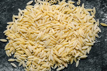 risoni pasta on gray and black background - close up