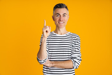 Happy handsome man smiling and pointing finger upward
