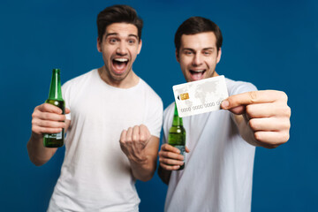 Excited handsome guys drinking bear and showing credit card