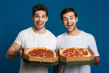 Excited handsome guys looking at camera while showing pizza