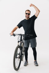 Fototapeta na wymiar Excited rider man making winner gesture while posing with his bicycle