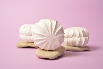 Close-up to three pieces of Russian traditional marshmallow dessert zefir (zephyr) souffle served on stones on on pastel violet background. Similarly with Meringue Dessert. Selective focus. Copy space