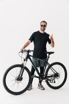 Happy rider man showing thumb up while posing with his bicycle