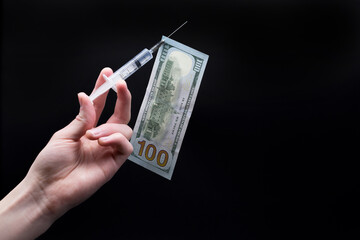 A dollar bill is attached to a medical syringe.