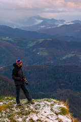 Obraz premium A photographer looking at the views of the snow-capped summit, on Mount Peñas de Aya in the town of Oiartzun near San Sebastián, Gipuzkoa. Basque Country