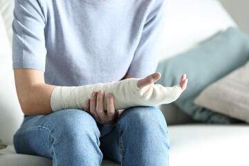 Disabled woman grabbing her painful bandaged arm - obrazy, fototapety, plakaty