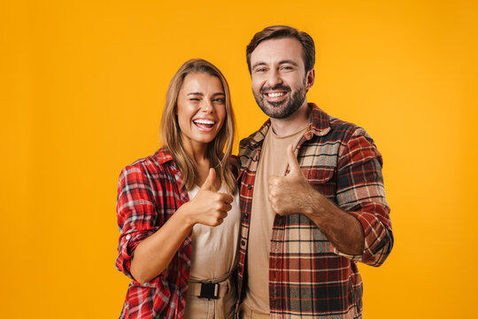 Joyful Couple Winking And Showing Thumbs Up While Hugging